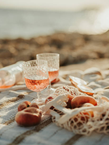 wein und pfirsiche am meer picknick im freien bei sonnenuntergang - roséwein stock-fotos und bilder