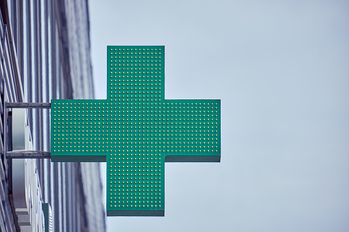 Green cross of a pharmacy store on the wall of a building, copy space