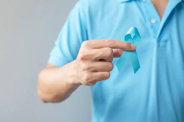 Photo of November Prostate Cancer Awareness month, Man in blue shirt with hand holding Blue Ribbon for supporting people living and illness. Healthcare, International men, Father and World cancer day concept