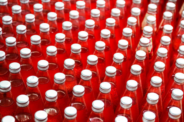 Group of red juice bottles with screw cap in conveyor belt at beverage processing plant
