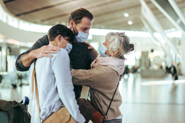 Senior woman receiving her family on arrival to airport Senior woman embracing and welcoming family at airport terminal after arrival. Senior man hugging her son on arrival to airport post pandemic. airport hug stock pictures, royalty-free photos & images