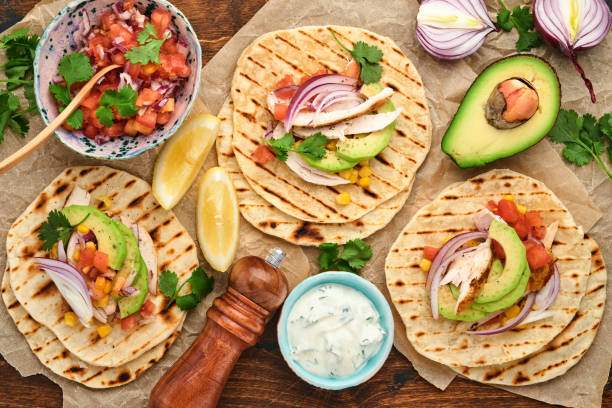 istock Mexican tacos with grilled chicken, avocado, corn kernels, tomato, onion, cilantro and salsa old wooden table. Traditional Mexican and Latin american street food. Top view. 1331972637