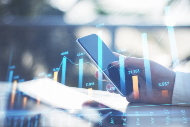 istock Close up of hand using smartphone with global forex chart on office desktop. Trade, online banking and finance concept. Double exposure. 1331975074