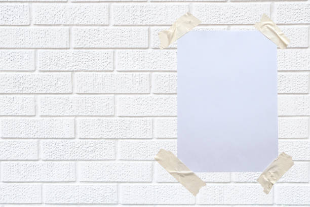 istock Blank white paper attached to the white wall with tape. 1331975189