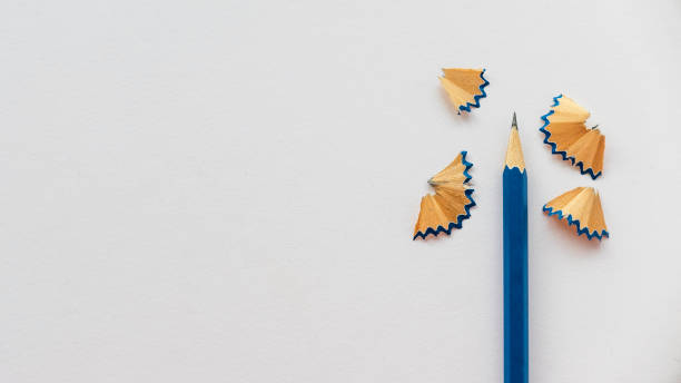 Blue pencil and its shaving on a blank white paper with copy space.