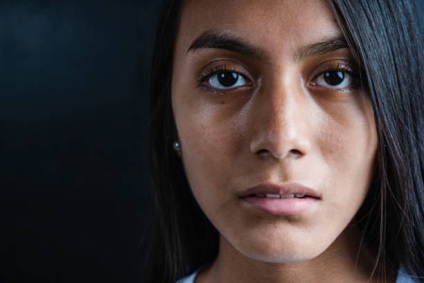 Close-up of a serious beautiful black haired Latina woman wearing a white T-shirt on a black background. Close-up of a serious beautiful black haired Latina woman wearing a white T-shirt on a black background. copy space. mediterranean woman portrait stock pictures, royalty-free photos & images