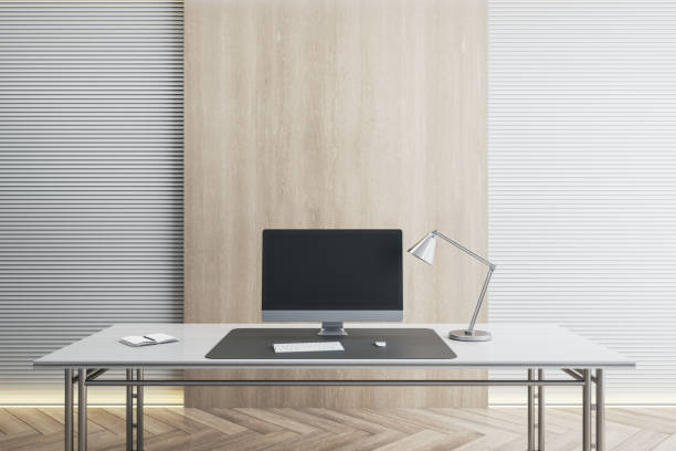 istock Desk with empty black computer monitor in modern white office interior with daylight and wooden flooring. Mock up, 3D Rendering. 1331976105