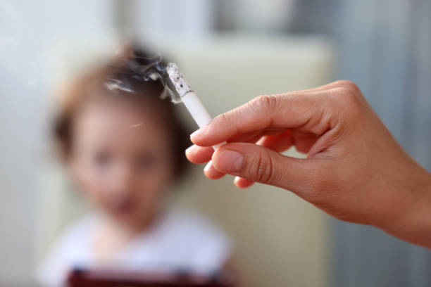 Baby girl behind a hand with a lighted cigarett - fotografia de stock