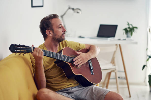 istock Man playing acoustic guitar at home. 1331978049