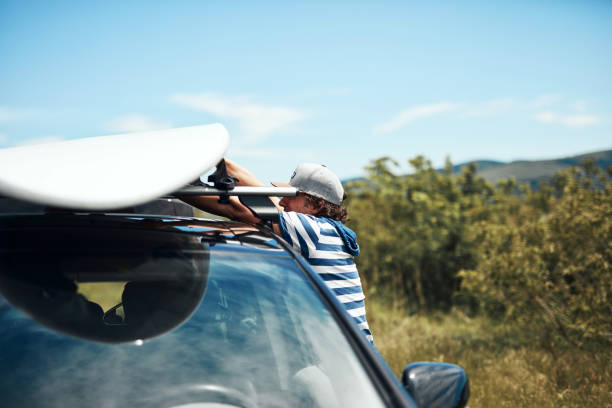 istock Windsurfer and camper packing and unpacking from a car in nature. 1331978144