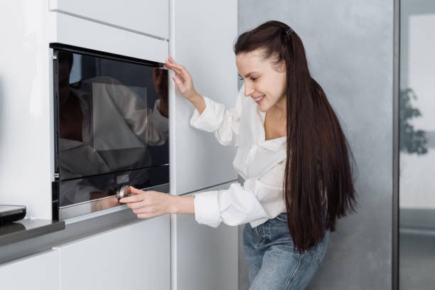 istock Smiling young woman turning microwave ovens knob 1331978210