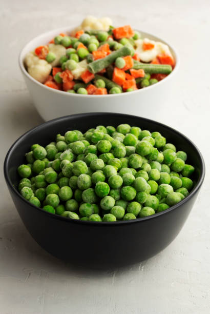 istock Frozen green peas in a grey bowl on light background 1331979216