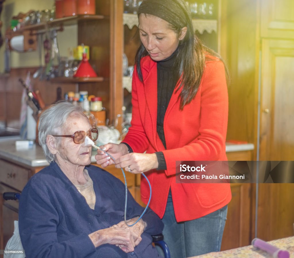 Family caring for family.Daughter helping elderly mom with N.G. tube for dysphagia Family caring for family.Daughter helping elderly mom with N.G. tube for dysphagia. Nasogastric Tube Stock Photo