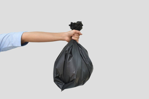 istock Hand holding a black garbage bag on grey background 1331981001