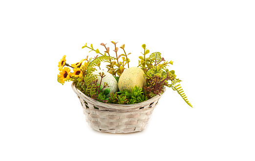 Handmade wicker basket with artificial flowers and Easter eggs. Copy space.