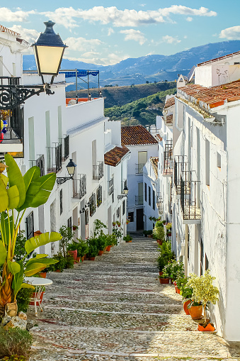 Narrow alley of an Andalusian town with its white houses and the mountains in the background. Frigiliana Malaga.