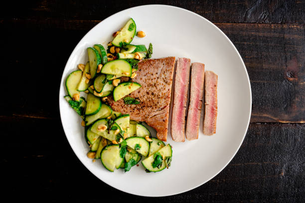 Tuna Steak with Cucumber-Peanut Salad Rare fish fillet served with cucumber and peanut salad as a side dish skipjack stock pictures, royalty-free photos & images