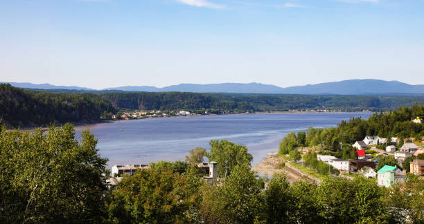 erhöhter blick auf den fluss saguenay über das dorf rivière-du-moulin an einem sommertag - chicoutimi travel locations nature city stock-fotos und bilder