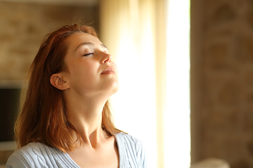 Redhead woman breathing fresh air at home