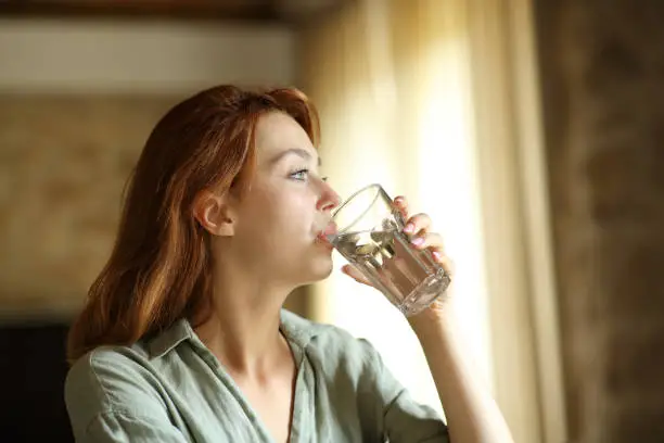 Woman drinking water from glass at home