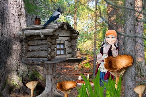 A hut on chicken legs stands in a fairy-tale, magical forest. A witch's dwelling, Baba Yagi with a  window and  a chimney in a forest thicket.Collage
