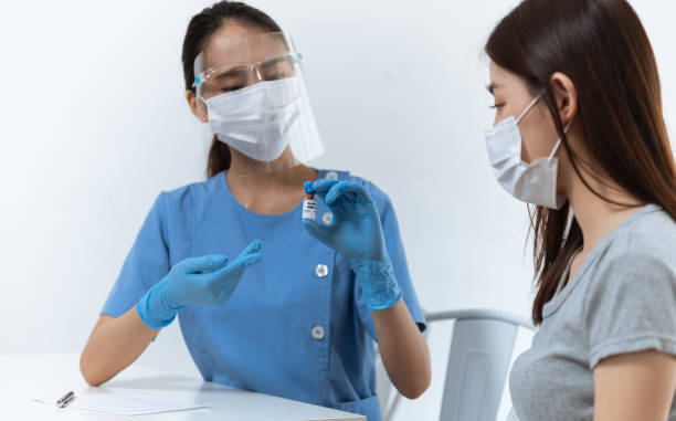 istock Young Asian nurse explaining covid19 vaccination process and side effect from coronavirus vaccine  to young Asian woman before injection at hospital or health center for prevent covid19 infection. 1331993357