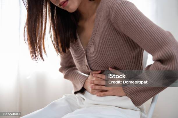 Healthcare Medical Or Daily Life Concept Close Up Stomach Of Young Lady Have A Stomachache Or Menstruation Pain Sitting On A Sofa Stock Photo - Download Image Now