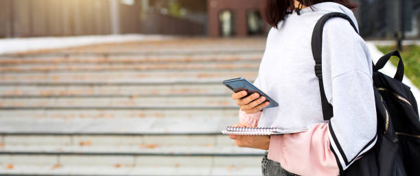 istock A female student with a black backpack holds a smartphone and Notepad on the threshold of the University. Higher education, the beginning of the school year, return to school, gadgets. Copyspace 1331994551