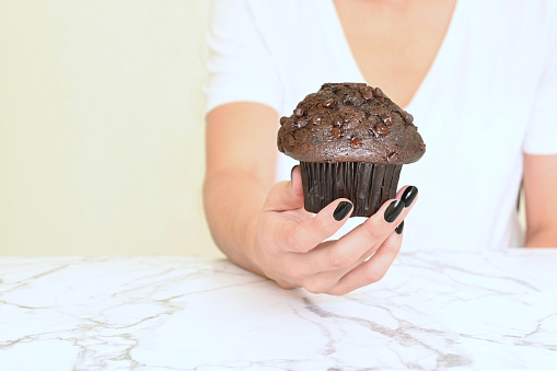 Young woman holding chocolate muffin