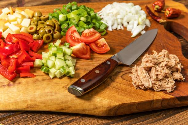 вкусный салат из тунца с овощами на деревянном столе. овощной салат с тунцом. приготовление полезного овощного салата с рыбой. диетическое � - tuna steak tuna steak olive oil стоковые фото и изображения