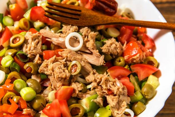 salada de atum saborosa com legumes na mesa de madeira. salada vegetal com atum. preparando uma salada vegetal saudável com peixe. comida dietética para atletas. - tuna steak tuna steak olive oil - fotografias e filmes do acervo