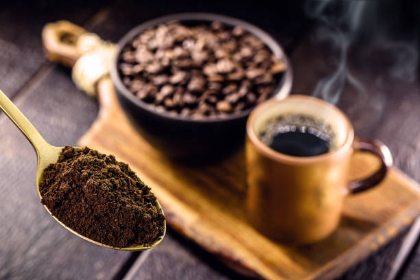 istock spoon with coffee powder and cup with hot coffee in the background, spot focus 1332003252