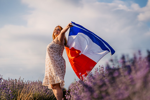 Young overweight beautiful woman with French flag in lavender field.