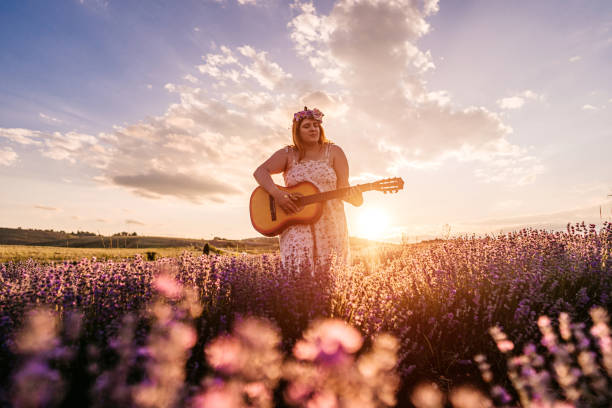 istock Woman playing guitar in lavender field at sunset 1332004585