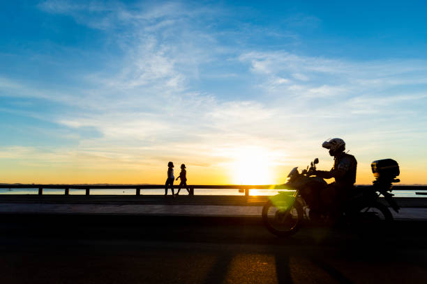 istock Silhouette of people at sunset riding a bicycle, exercising, walking. 1332004814