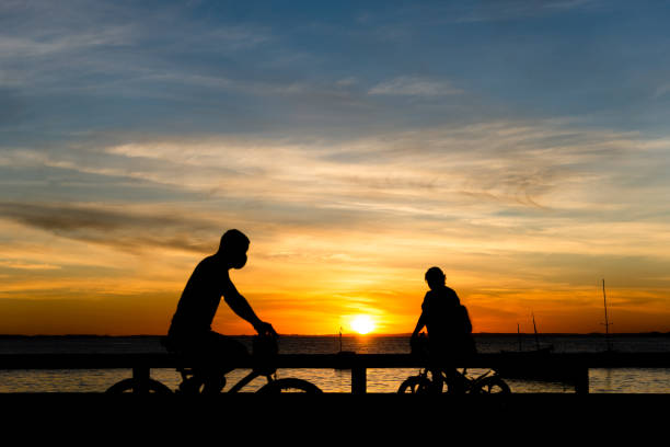 istock Silhouette of people at sunset riding a bicycle, exercising, walking. 1332004824