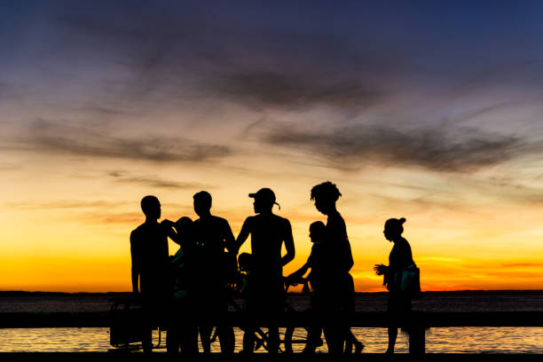 Salvador, Bahia, Brazil - May 27, 2021: Silhouette of people walking, running, talking and enjoying the sunset on Ribeira beach.