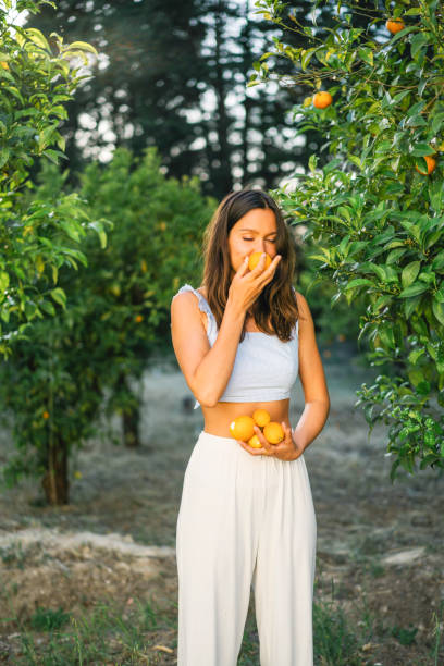 istock Young woman smells freshly picked oranges from tree 1332007416