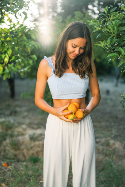 istock Young woman holds freshly picked oranges from tree 1332007529
