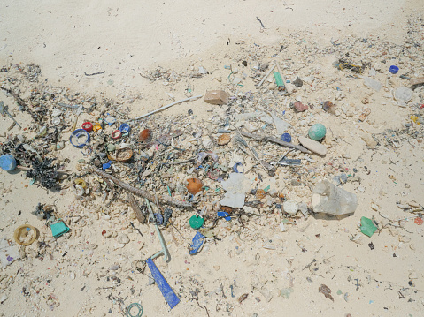 Plastic bottles and other garbage on white sand beach