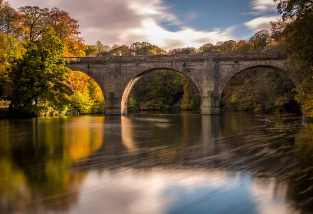 A long exposure of a beautiful arched bridge near Durham Cathedral with the autumn colors reflecting in the River Wear A long exposure of a beautiful arched bridge near Durham Cathedral with the autumn colors reflecting in the River Wear. river wear stock pictures, royalty-free photos & images