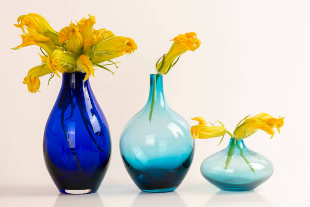 istock Decorative fresh zucchini flowers in blue vases on white background with space for text 1332014444