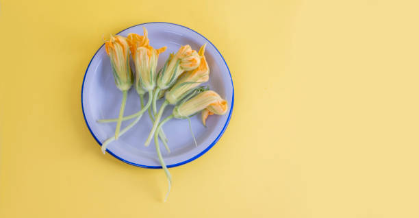 istock Top view on plate with zucchini flowers on yellow background with space for text 1332014449