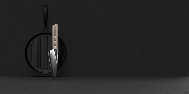 couteau de chef brillant et brillant devant une poêle noire sur fond noir - cooks knife photos et images de collection