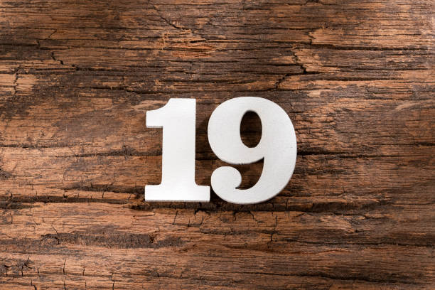 istock Number nineteen 19 - White Piece on Rustic Wood Background 1332021750