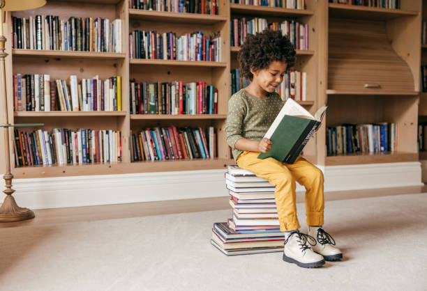 улыбающийся дошкольник держит книгу - child at library стоковые фото и изображения