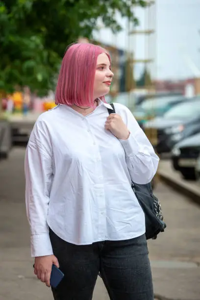 Outdoors portrait of 20 year old woman in white shirt with pink hair