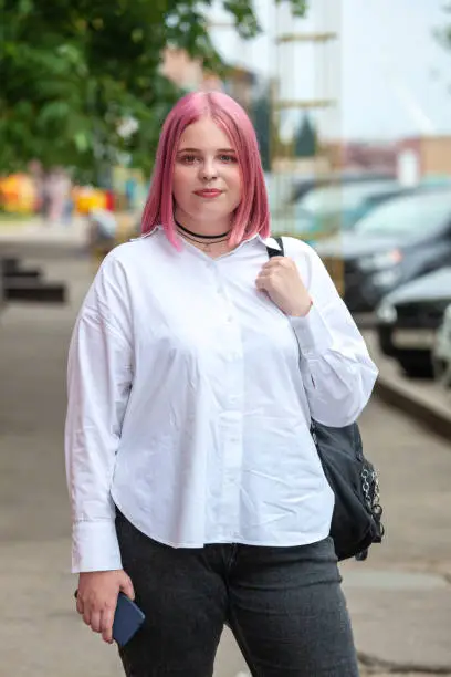Outdoors portrait of 20 year old woman in white shirt with pink hair