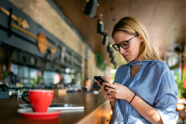 una giovane imprenditrice molto attraente si sta godendo una bevanda calda al bar e sta facendo alcuni piani aziendali sul suo telefono cellulare. - telephone worried one person discussion foto e immagini stock