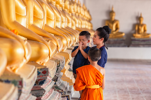 Mother and son praying respect buddha statue in Wat Phutthai Sawan Temple, Ayutthaya, Thailand. Thai culture concept